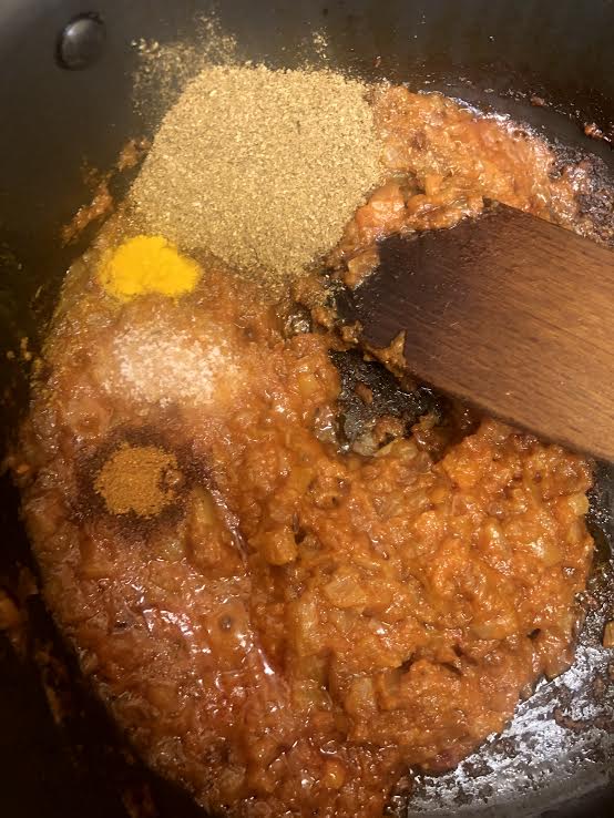 Spices added to tomato in pot
