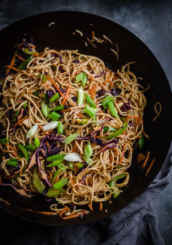 Hakka Noodles in Wok topped with Spring Onions on grey towel
