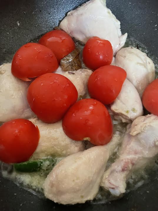 Tomato halves on top of chicken in wok