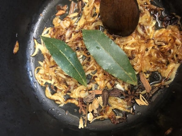 Bay leaves and whole spices added to caramelised onions