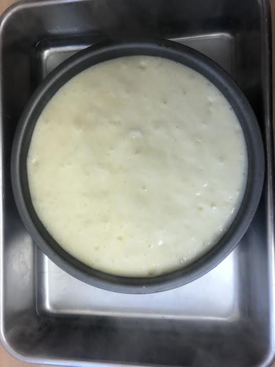 Cheesecake batter in tin in larger roasting tin with water in it