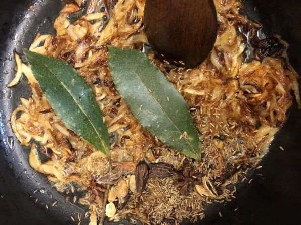 Whole garam Masala and cumin seeds in pot with onions