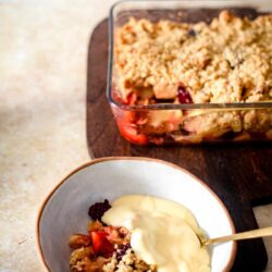 Apple and Blackberry Crumble in bowl with custard