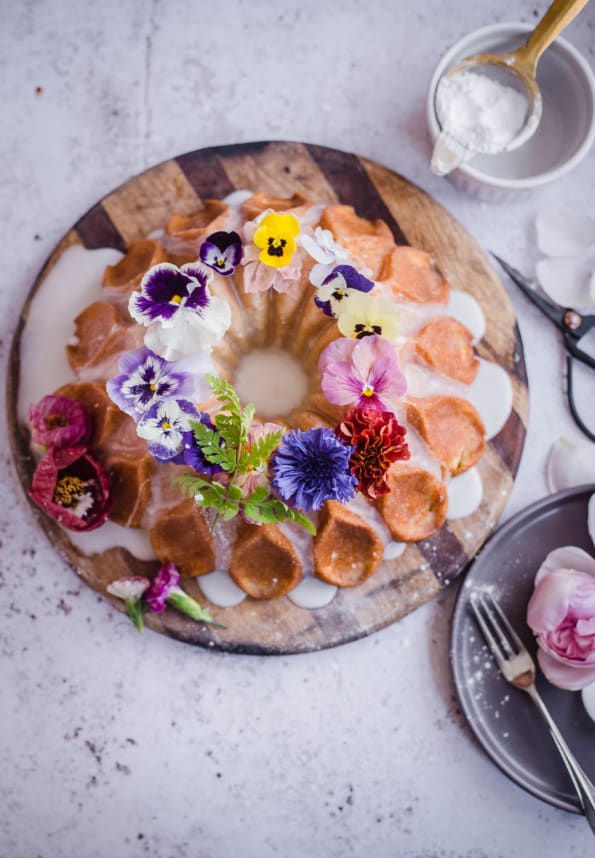 Bundt cake with edible flowers on a wooden board 