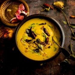Palak Dal in a bowl with tadka ingredients on top and around