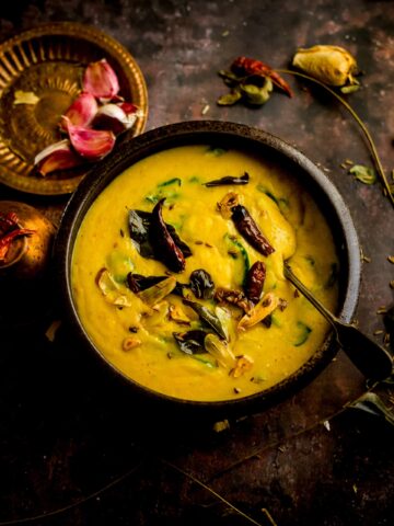 Palak Dal in a bowl with tadka ingredients on top and around