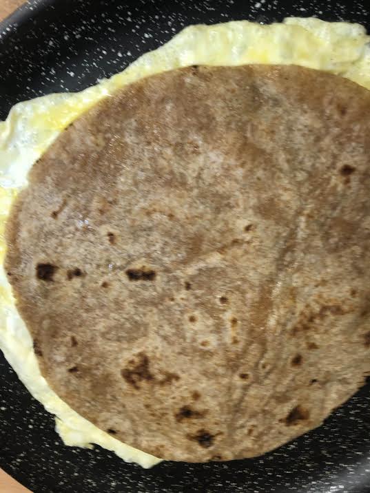 Roti on top of omelette in griddle pan