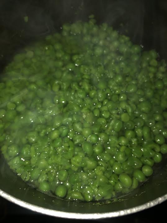 Boiled frozen peas in pot