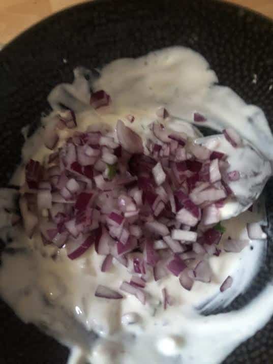 Onions, Mint, yoghurt and salt being mixed in a bowl