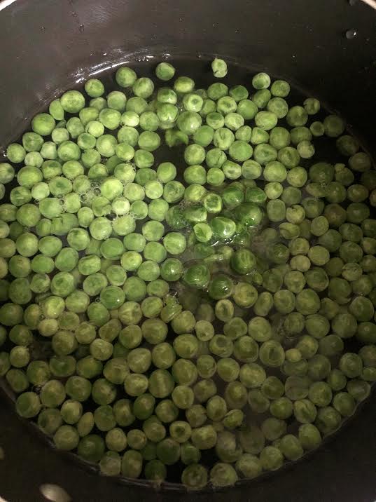 Frozen peas and water in pot