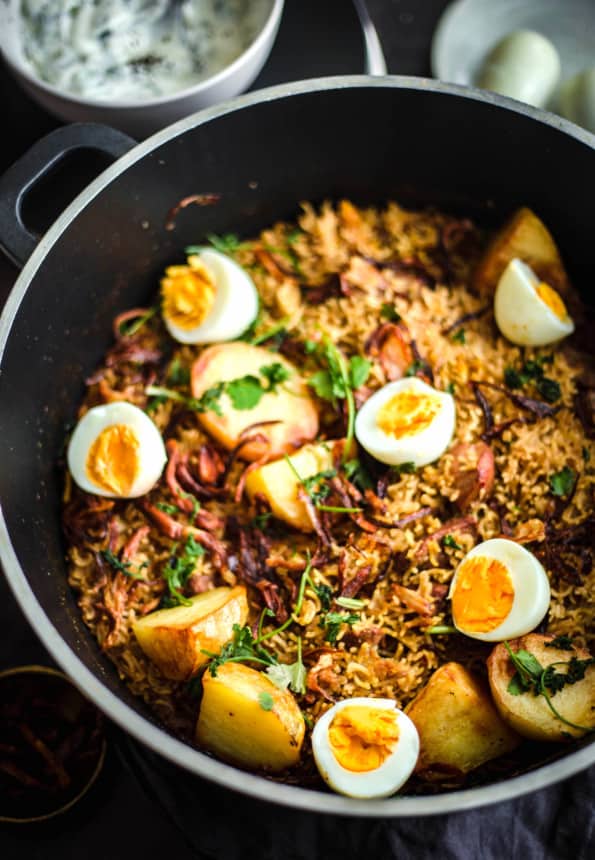 Pakistani Chicken Biryani Recipe in a pot with Eggs on top and salad to back