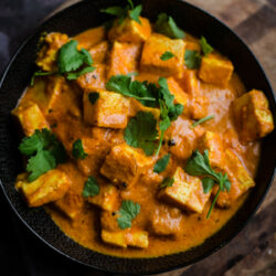 Paneer Makhani in a black bowl on wooden board
