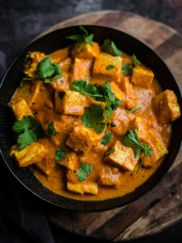 Paneer Makhani in a black bowl on wooden board