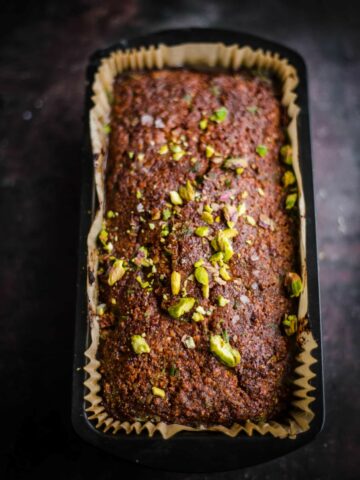 Pistachio Loaf Cake in a loaf tin with pistachios on top