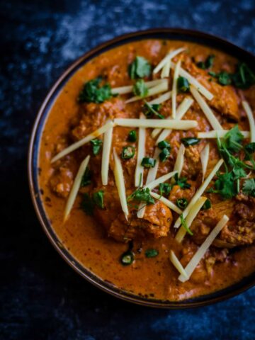 Patiala Chicken in a blue bowl topped with slivered ginger and coriander