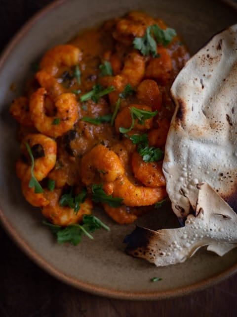 Prawn Masala in plate with papadum to side
