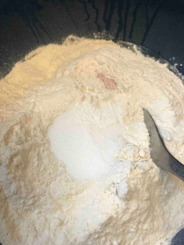 Flour, Salt and Sugar added to bowl with a spoon in it