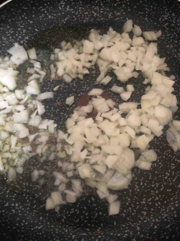 Onions and cumin seeds frying in oil and ghee
