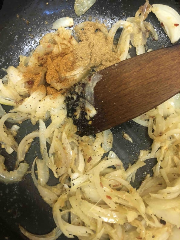 Cumin added to golden onions in wok