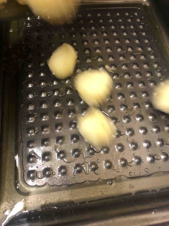 Potatoes being added to hot oil in pan