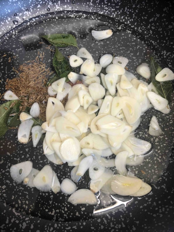 Sliced garlic added to oil in pan