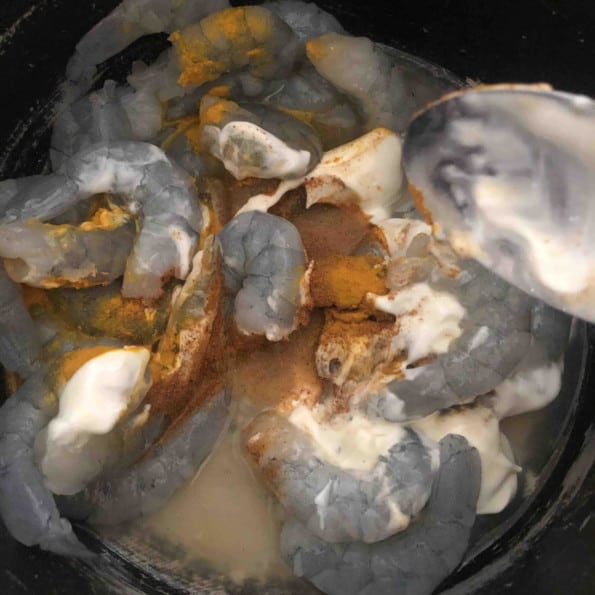 Prawns being marinaded in a bowl with yoghurt and spices