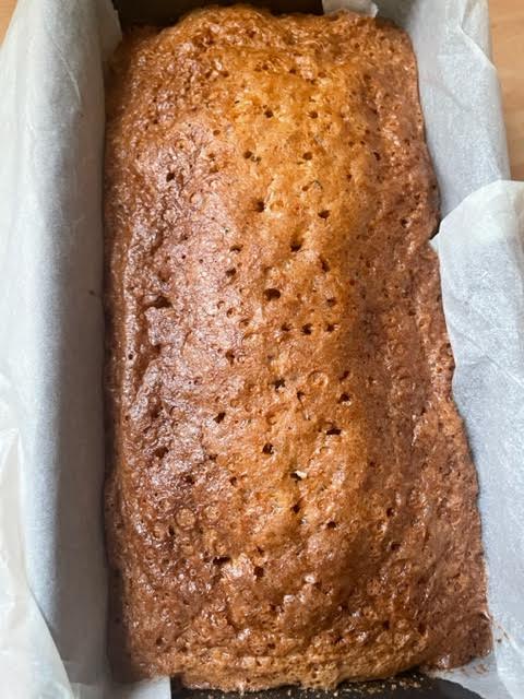Loaf cake in lined tin with holes poked all over