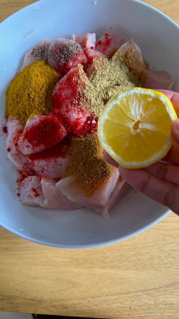 Tandoori Chicken Tikka Bites or Kebab Skewers Lemon added to chicken in bowl