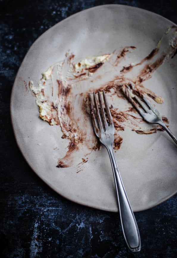 A plate with 2 forks and leftover cream and nutella from eaten dessert