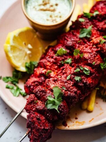 Tandoori chicken skewers in plate with chips and sauce