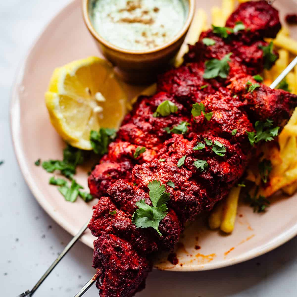 Tandoori Chicken Tikka Bites or Skewers Tandoori chicken skewers in plate with chips and sauce