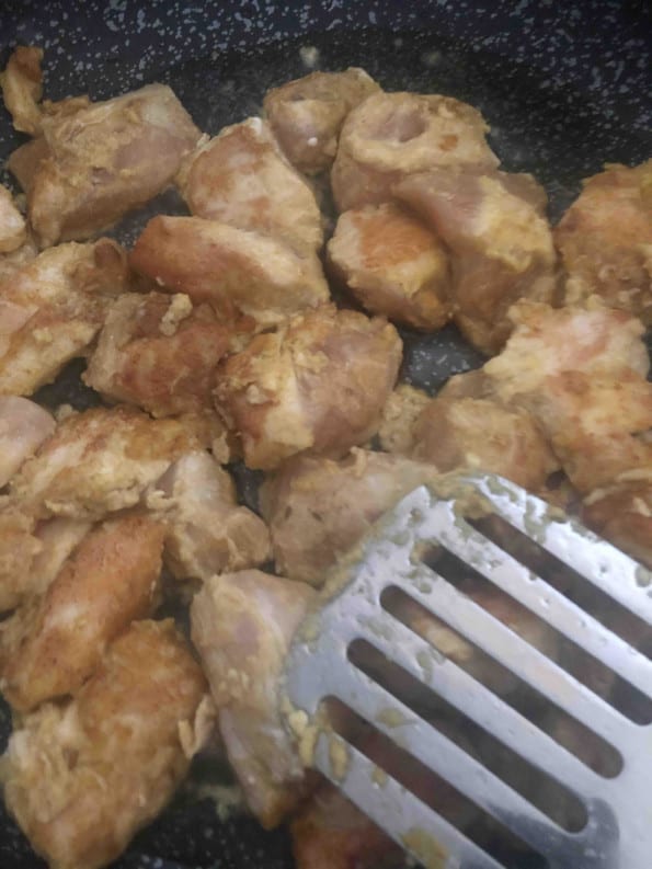 Chicken being fried in a pan 