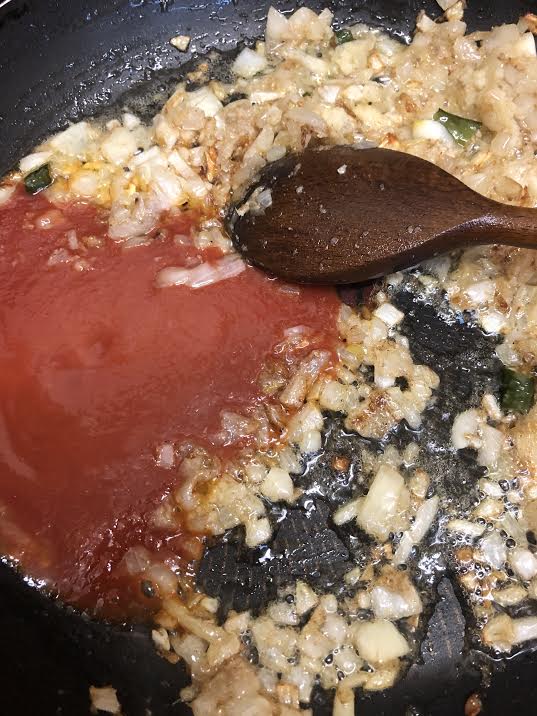 Tomatoes added to golden onions in pan