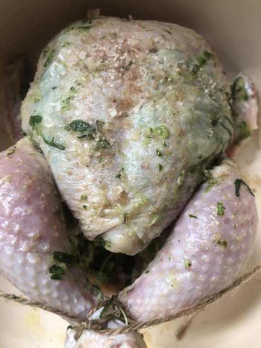 Chicken with legs tied together and butter smeared on top