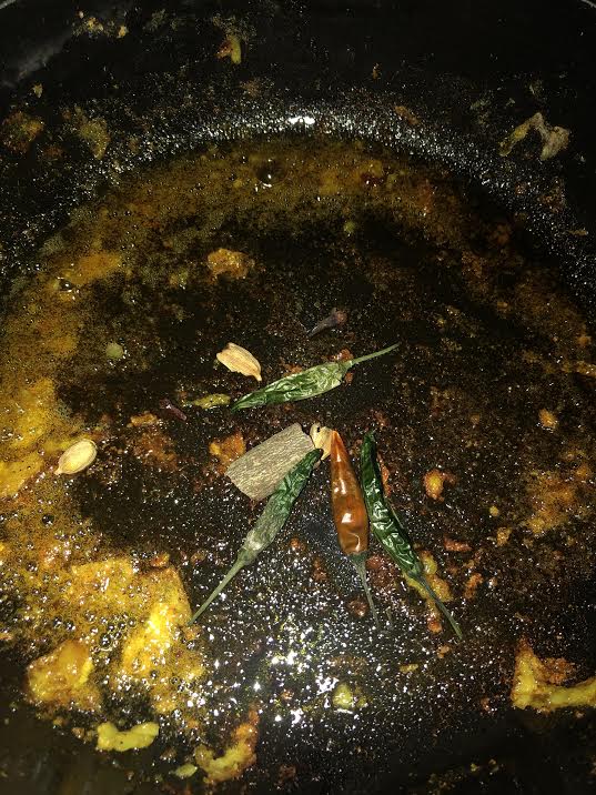 Whole spices cooking in oil in pot