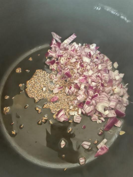 Onions and cumin in oil in pot