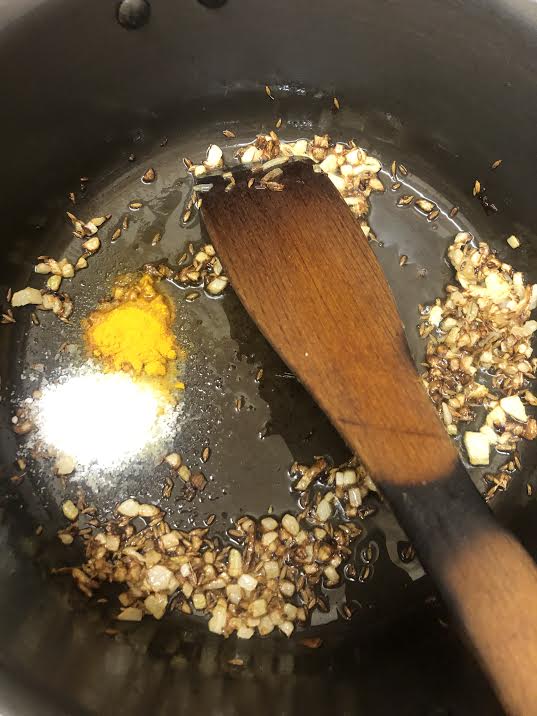 Bronwed onion, salt and turmeric in a pot