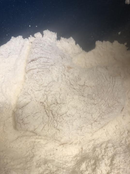 Chicken being dredged in seasoned flour