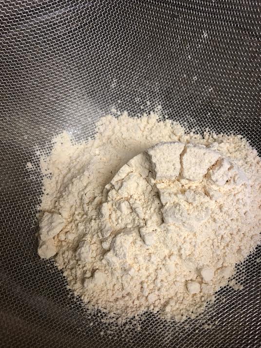 Gram Flour in a sieve over bowl
