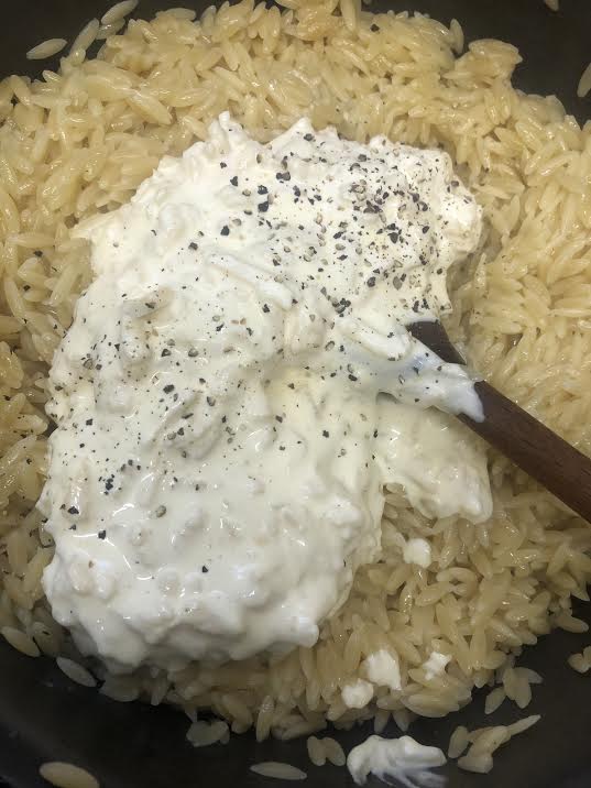 Sauce and Orzo in pot being stirred with spoon