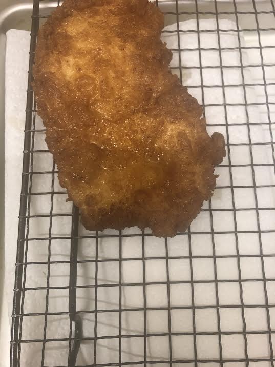 Fried chicken on a wire rack over a tissue lined tray