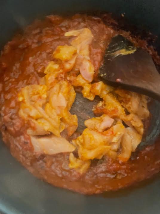 Chicken added to pasta sauce on stove