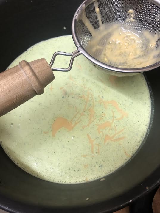 Gram flour being sieved into yoghurt mix