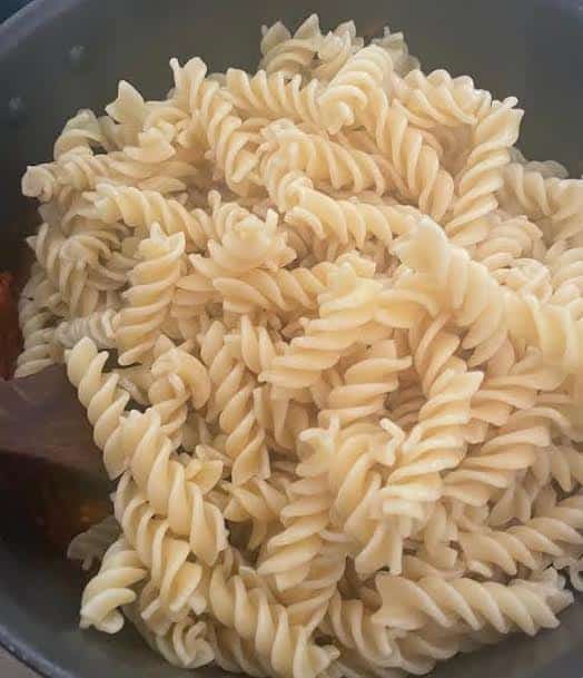 Pasta added to pasta sauce in pot