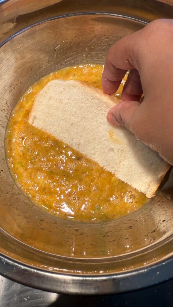 Savoury Masala French Toast Bread being dipped in egg
