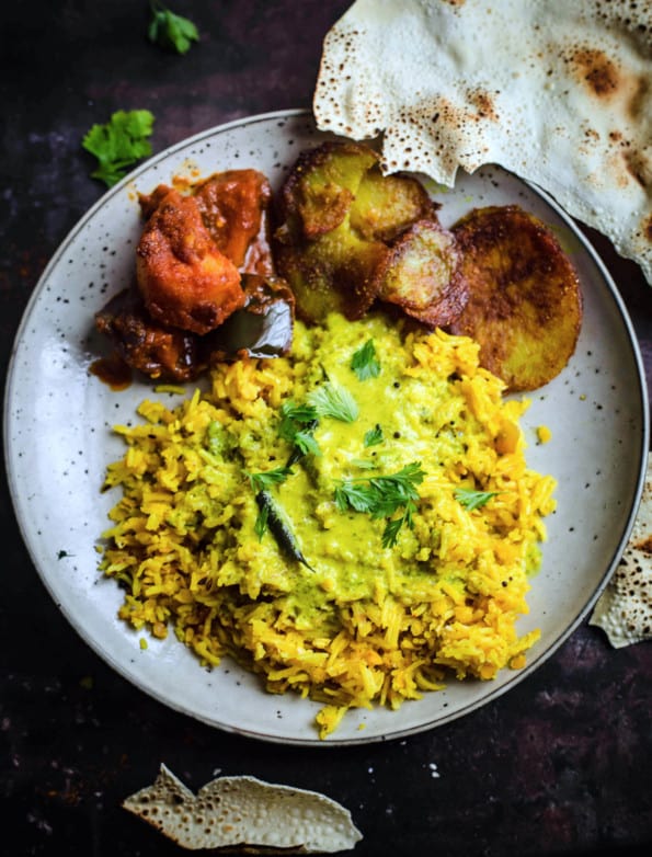 Kadhi Khichdi in a plate with papadums, potatoes and aubergine