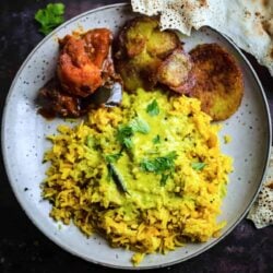 Kadhi Khichdi in a plate with papadums, potatoes and aubergine