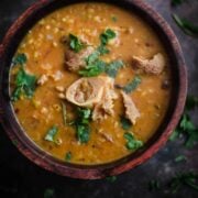 Haleem in a wooden bowl with coriander on top