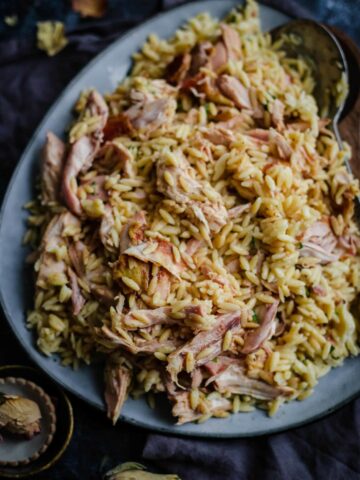 Chicken Orzo on a blue platter with flowers scattered around sides