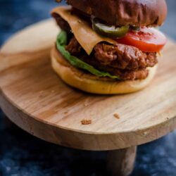Buttermilk Chicken Burger on a stool with pickles, salad and cheese